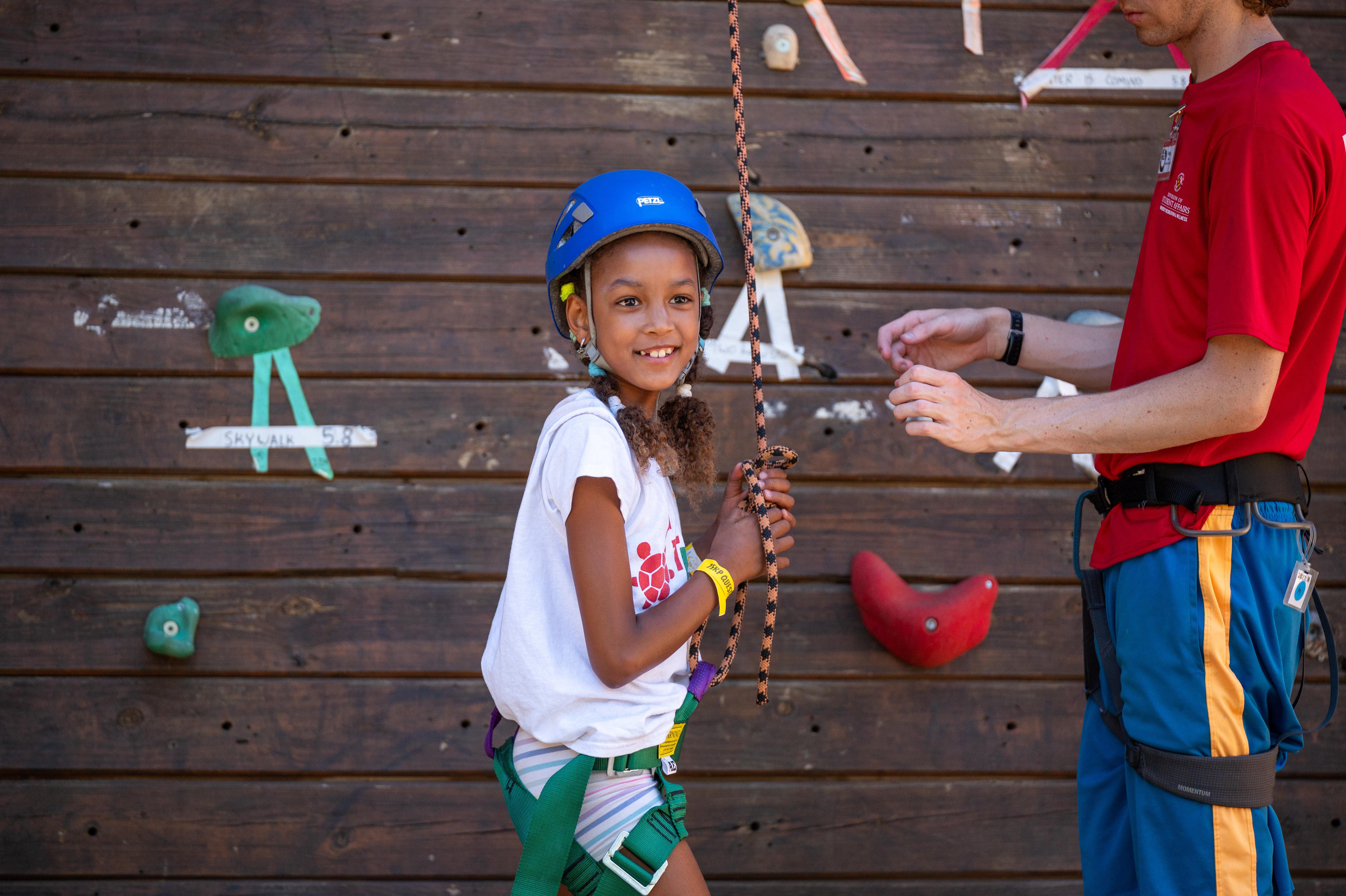 Campers smiling while preparing to climb the wall