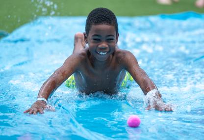 Small child going down slip and slide smiling on RecWell La Plata Turf